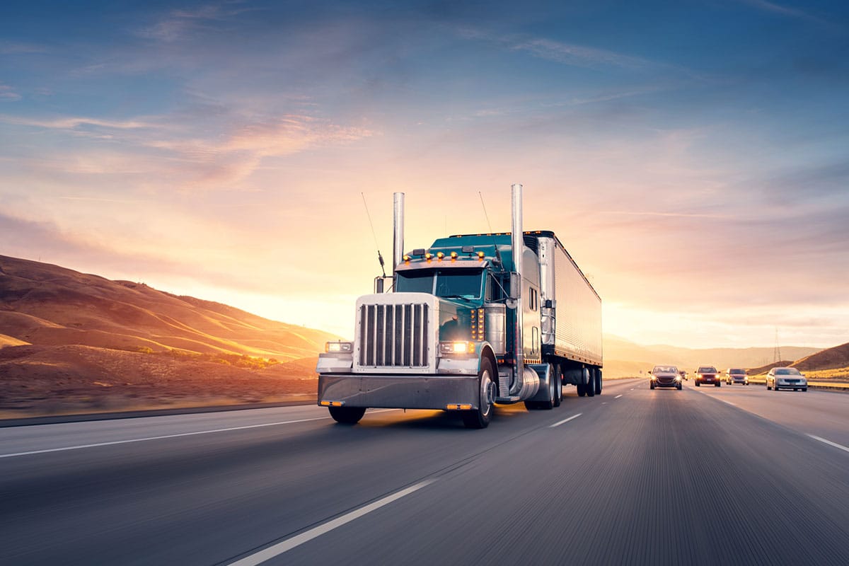 Un gros semi-remorque commercial circule sur une autoroute au moment d'un coucher de soleil pittoresque.