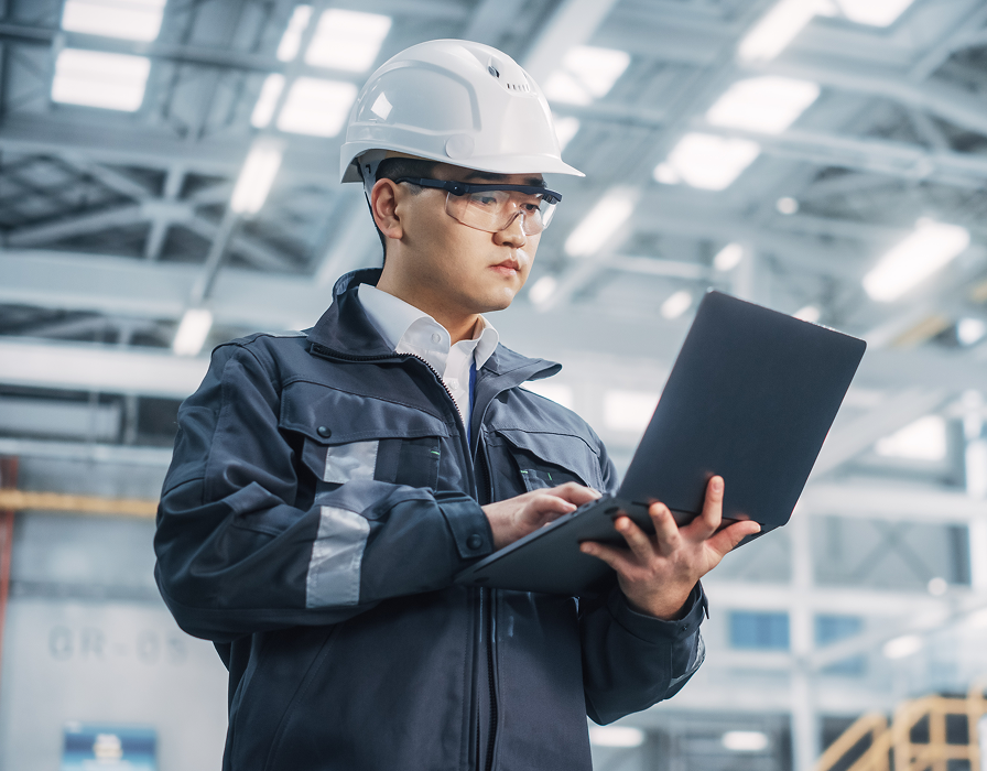 Un employé dans une usine de fabrication utilisant un ordinateur portable qui tire parti des technologies de l’industrie 4.0 et de l’IdO.