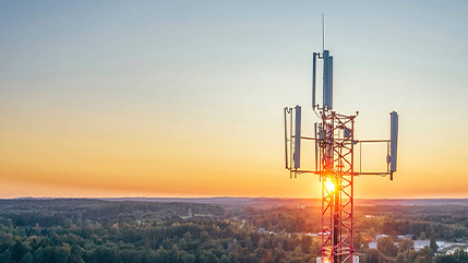 Une tour cellulaire au coucher du soleil surplombe un vaste paysage, ce qui représente une mobilité sécurisée et fiable et une vaste couverture 5G qui aide le personnel gouvernemental à rester connecté, productif et en sécurité grâce à Bell.