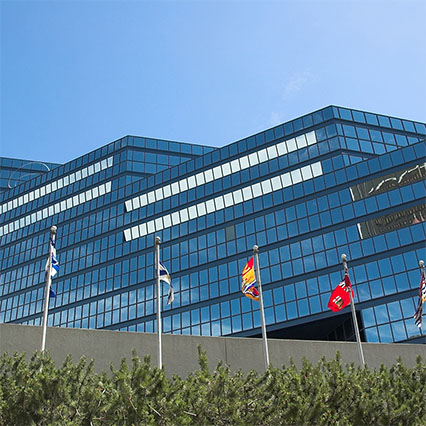 Plusieurs drapeaux flottent devant l’Édifice municipal de Calgary, qui symbolise les gouvernements municipaux soutenus par un savoir-faire local, une connectivité moderne et des solutions numériques partout au Canada.