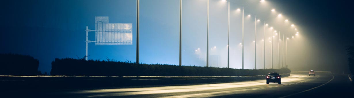 Smart street lights on dark highway at night helping to decrease energy costs while reducing carbon emissions.